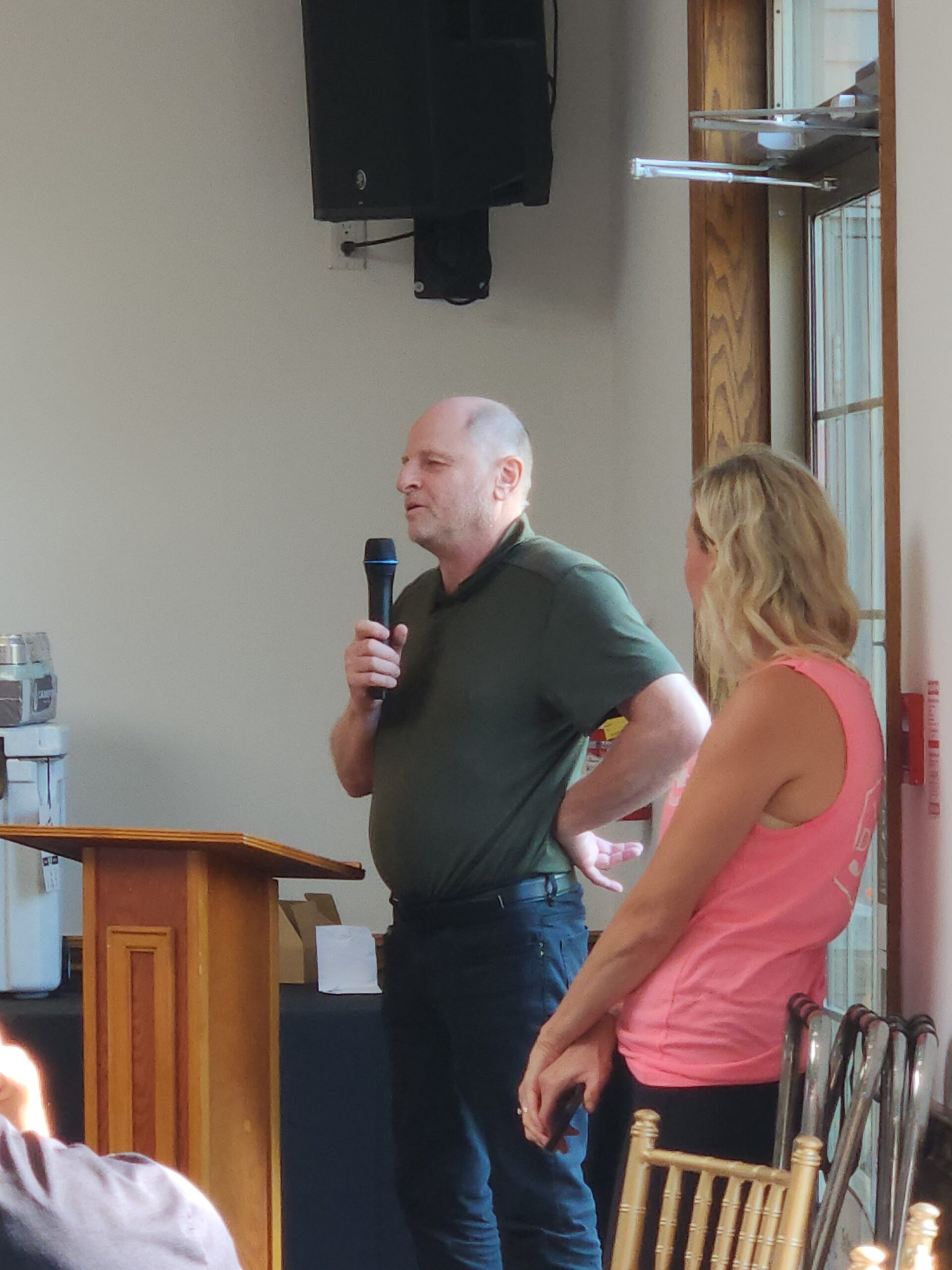 Peter stands at a podium speaking into a microphone 