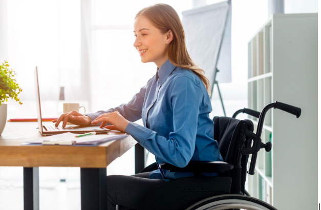 A lady sitting on a wheelchair operating a computer